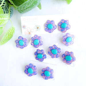 Step into a burst of color with the Aqua Bloom earrings. These vibrant handmade earrings feature unique floral shapes with a pop of aqua blue, perfect for adding a fun touch to any outfit.