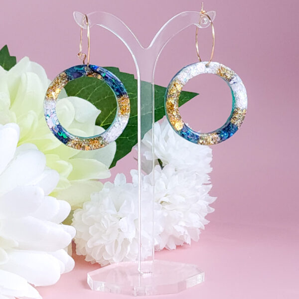 Embrace celestial beauty with Night Sky Orbit earrings from Orellie. Featuring glittering accents of gold and blue, these handmade hoops add elegance to every look, whether casual or formal.