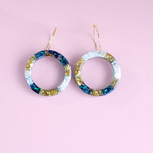 Embrace celestial beauty with Night Sky Orbit earrings from Orellie. Featuring glittering accents of gold and blue, these handmade hoops add elegance to every look, whether casual or formal.