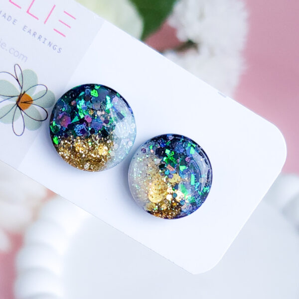 Add a celestial touch with the Night Sky Gems from Orellie. These stunning round stud earrings shimmer with a cosmic blend of glitter and hues, perfect for any occasion or everyday sparkle.