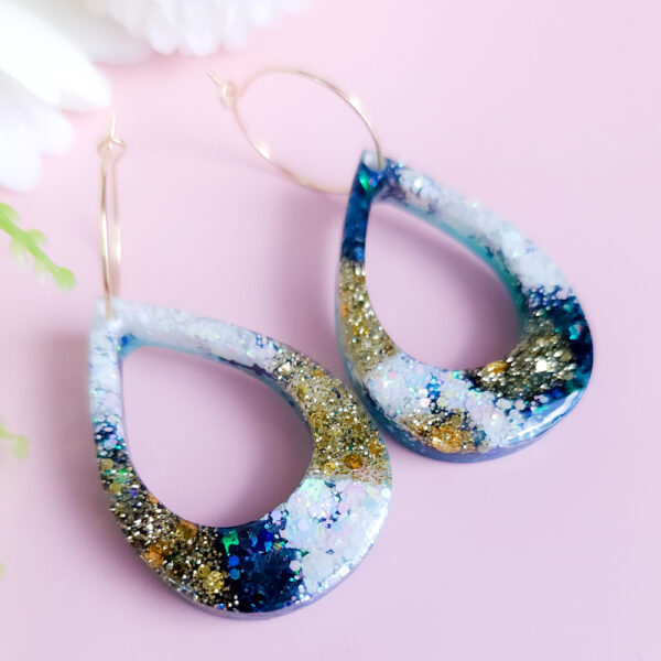 Add celestial charm to your style with the Night Sky Teardrops earrings from Orellie. These handmade teardrop earrings shimmer with golden and green glitter, evoking the magic of a starry night. Perfect for any occasion.