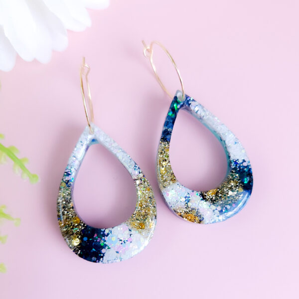 Add celestial charm to your style with the Night Sky Teardrops earrings from Orellie. These handmade teardrop earrings shimmer with golden and green glitter, evoking the magic of a starry night. Perfect for any occasion.